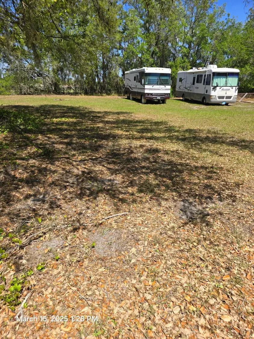 Two motorhomes parked on the grass lot at Granada Blvd Vehicle Storage in Kissimmee