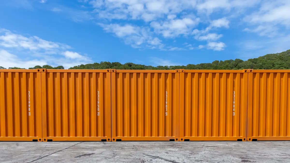 Orange shipping containers stacked in the sun