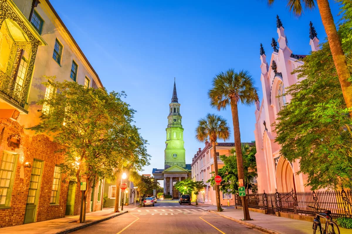 A Charleston street at dusk beneath a church steeple