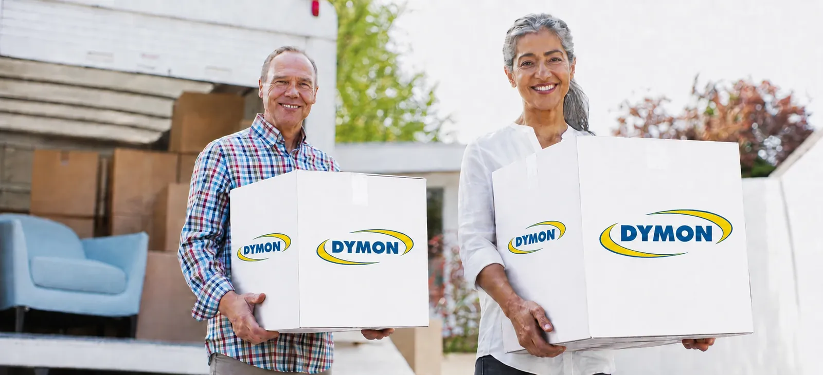 Two people carrying DYMON boxes from a moving truck